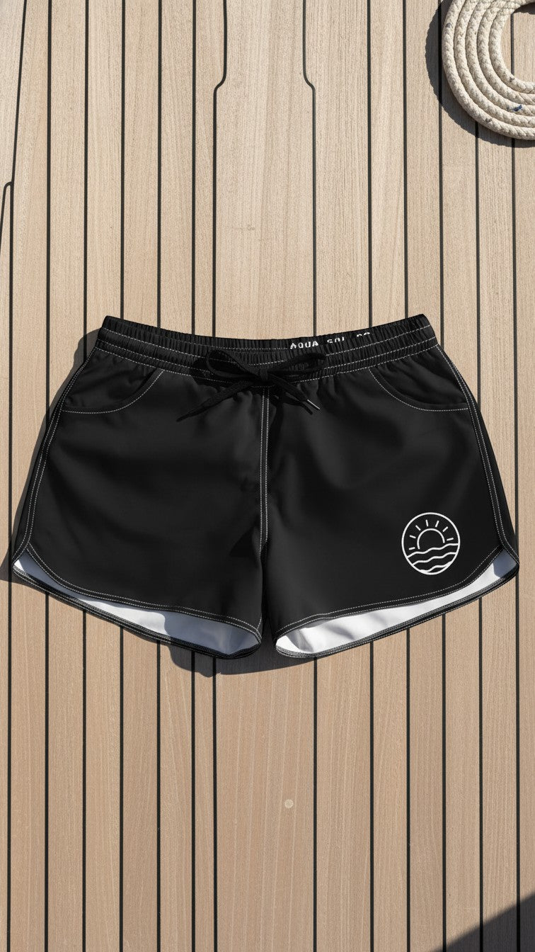Aqua Sol Company black quick-dry coastal shorts with white contrast stitching, drawstring waist, and sunrise emblem.